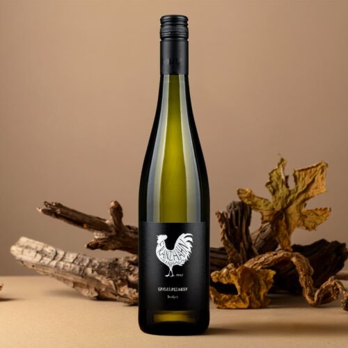 Eine Flasche Grauburgunder-Weißwein mit einem schwarzen Etikett, auf dem ein weißer Hahn abgebildet ist, steht auf einer beigen Fläche, umgeben von Treibholzstücken und getrockneten Blättern vor einem neutralen Hintergrund.